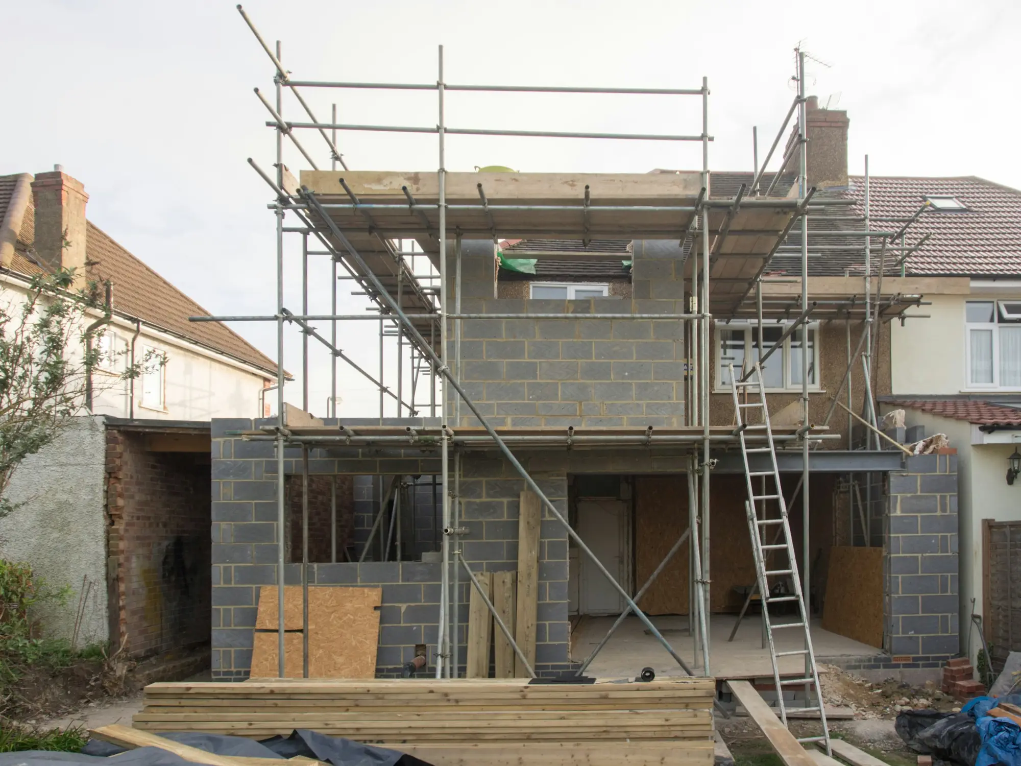Modern residential home extension under construction with scaffolding and blockwork